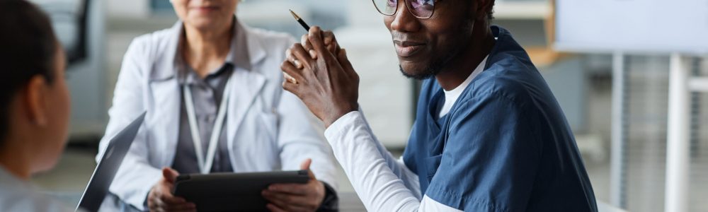 Focus on young African American assistant in uniform looking at colleague